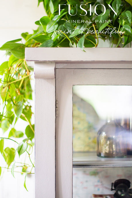 White cabinet with glass door, labeled “Cobblestone by Fusion Mineral Paint”.