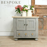 Gray cabinet in Cobblestone by Old Fashioned Milk Paint with white floral pitchers on top.