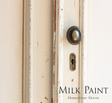 Distressed cream door with knob, keyhole, and “Combed Wool Milk Paint by Homestead House” label.