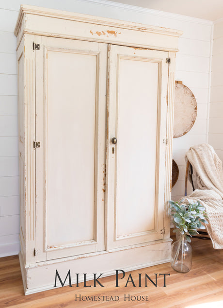 Cream-colored wardrobe painted in Homestead House Combed Wool Milk Paint, shown on wood floor.