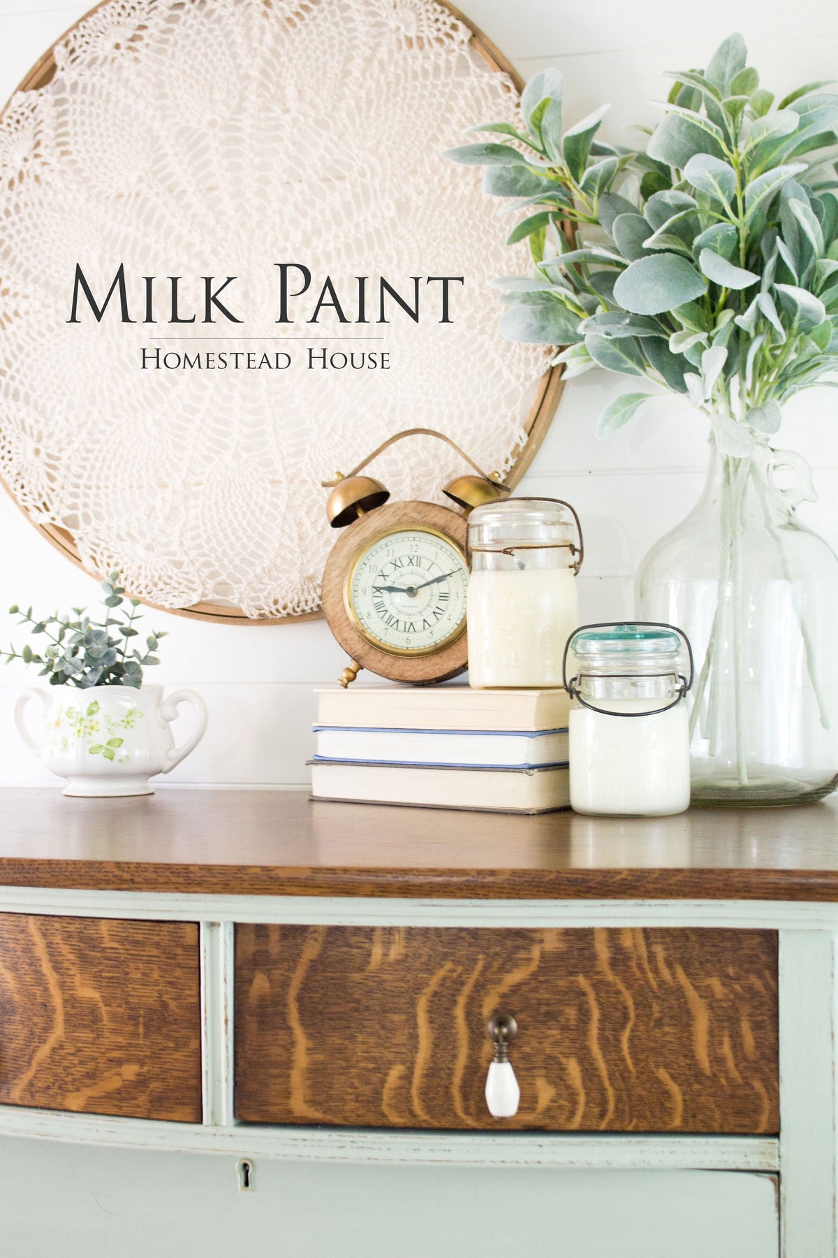 Dresser with books, a clock, milk jars, and Homestead House Craftsman Milk Paint accents; doily art in background.