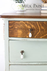 Wooden dresser with green Craftsman Milk Paint by Homestead House drawers, dark wood top, and ceramic pulls.
