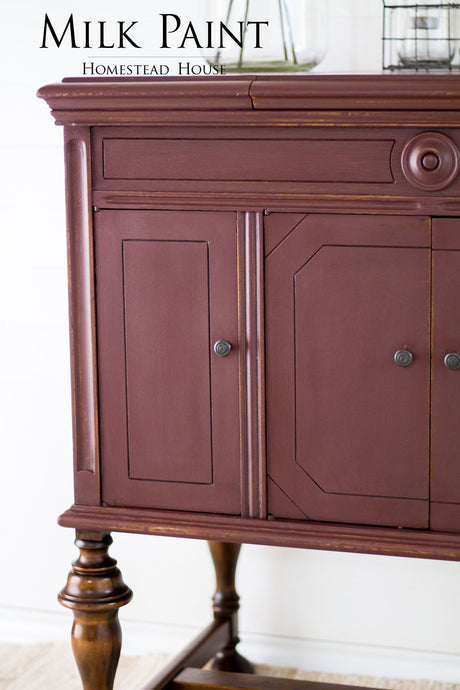 Wooden cabinet with ornate legs, shown against a white wall. Text: Cranberry Milk Paint by Homestead House.