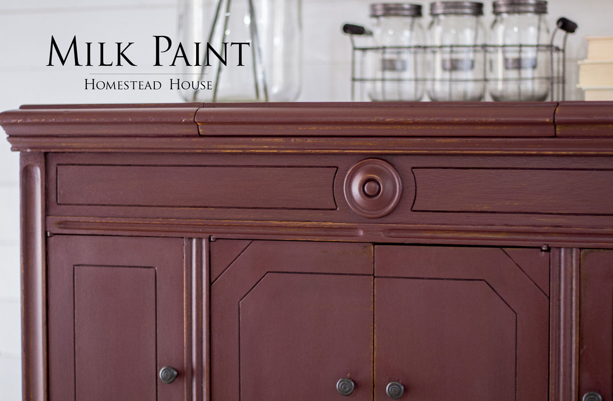 Maroon cabinet painted in Cranberry Milk Paint by Homestead House, showing visible wood grain.