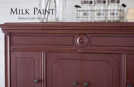 Maroon cabinet painted in Cranberry Milk Paint by Homestead House, showing visible wood grain.