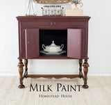 Dark wood sideboard with open door revealing white dish; text reads Cranberry Milk Paint by Homestead House.