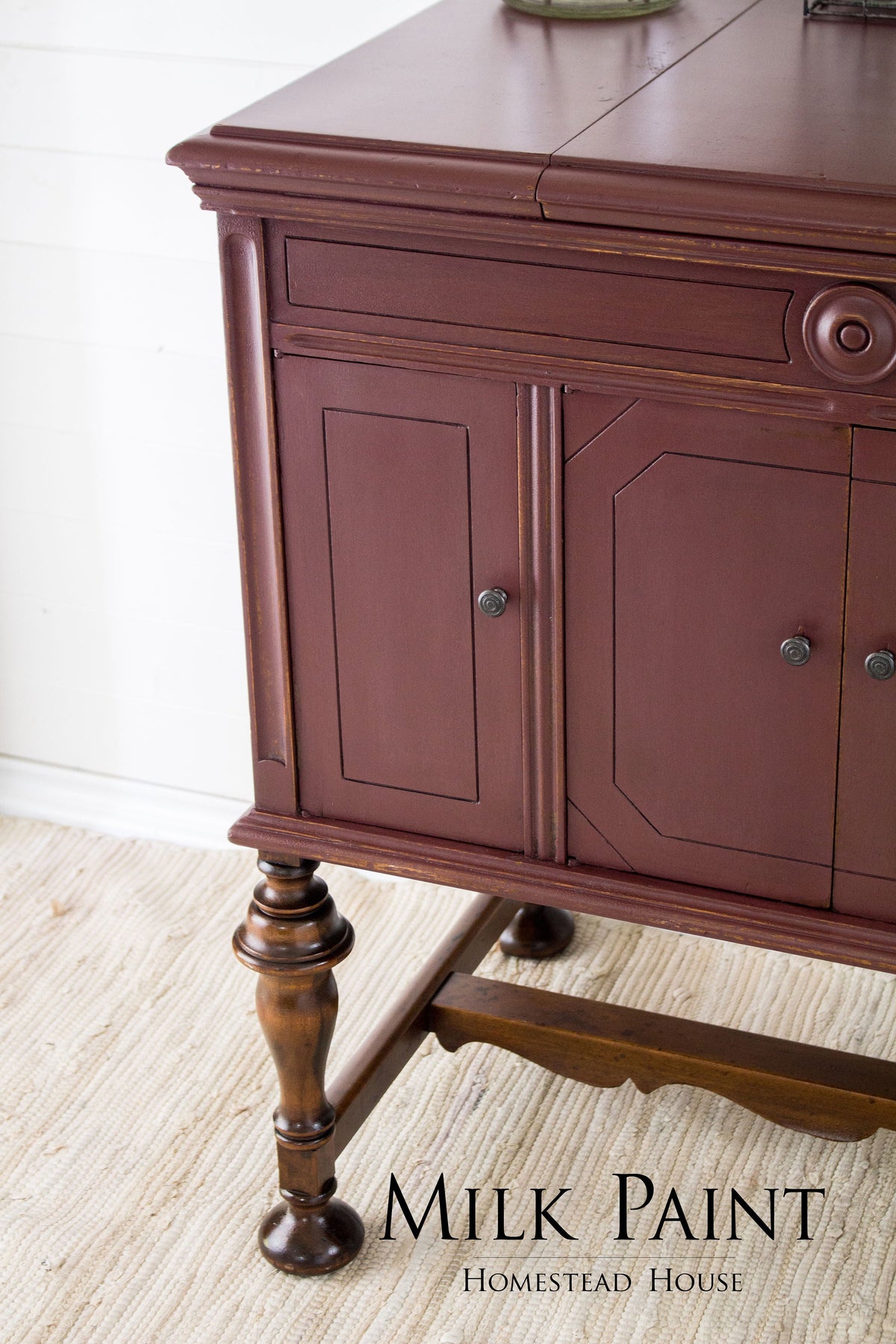 Homestead House Cranberry Milk Paint wooden sideboard with paneled doors and elegant legs on a beige rug.
