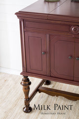 Homestead House Cranberry Milk Paint wooden sideboard with paneled doors and elegant legs on a beige rug.
