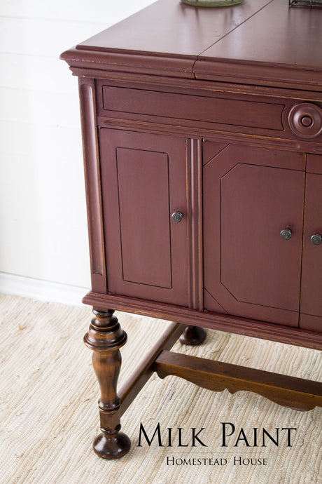 Homestead House Cranberry Milk Paint wooden sideboard with paneled doors and elegant legs on a beige rug.