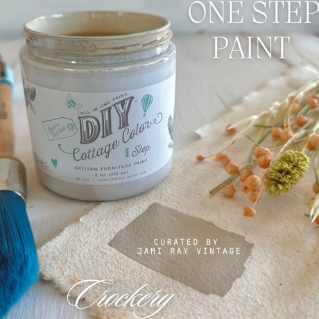 Open Crockery Cottage Color by DIY Paint Co. with water-based paint, blue brush, dried flowers, and fabric swatch.