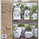 Five white jars with I.O.D. Crockery Stamp vintage labels, each topped with a green plant.