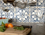 Cutting board with vegetables, knife, water glass, and I.O.D. Cubano Tile Stamp (Retired) on blue tile backsplash.