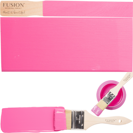 Two brushes, CUREiously Pink Fusion Mineral Paint jar, and pink paint swatches on wood.