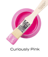 Paintbrush with pink acrylic resting on a jar of CUREiously Pink (Limited Release) Fusion Mineral Paint.