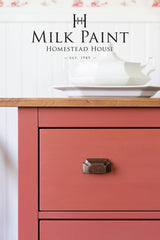 Red cabinet in Dala Red Milk Paint by Homestead House, brass handle, wood top, teapot on surface.