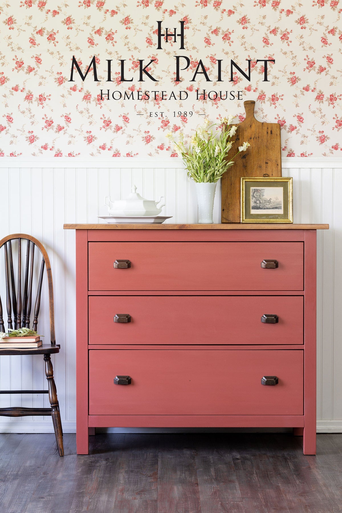 Dresser painted in Dala Red Milk Paint by Homestead House, shown near books and a chair.