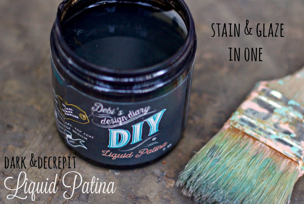 Open DIY Paint Co. Dark & Decrepit Liquid Patina bottle next to a teal brush.