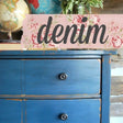 Blue dresser in Old Fashioned Milk Paint Denim with black knobs, topped with a globe and “denim” floral sign.