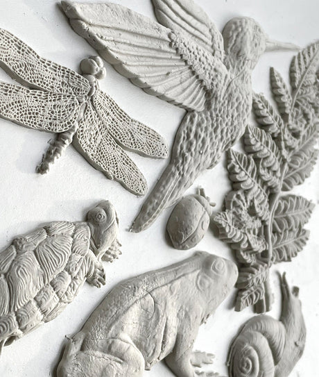 I.O.D. Dewdrop Pond Mould clay relief with dragonfly, beetle, turtle, and fern details on white background.