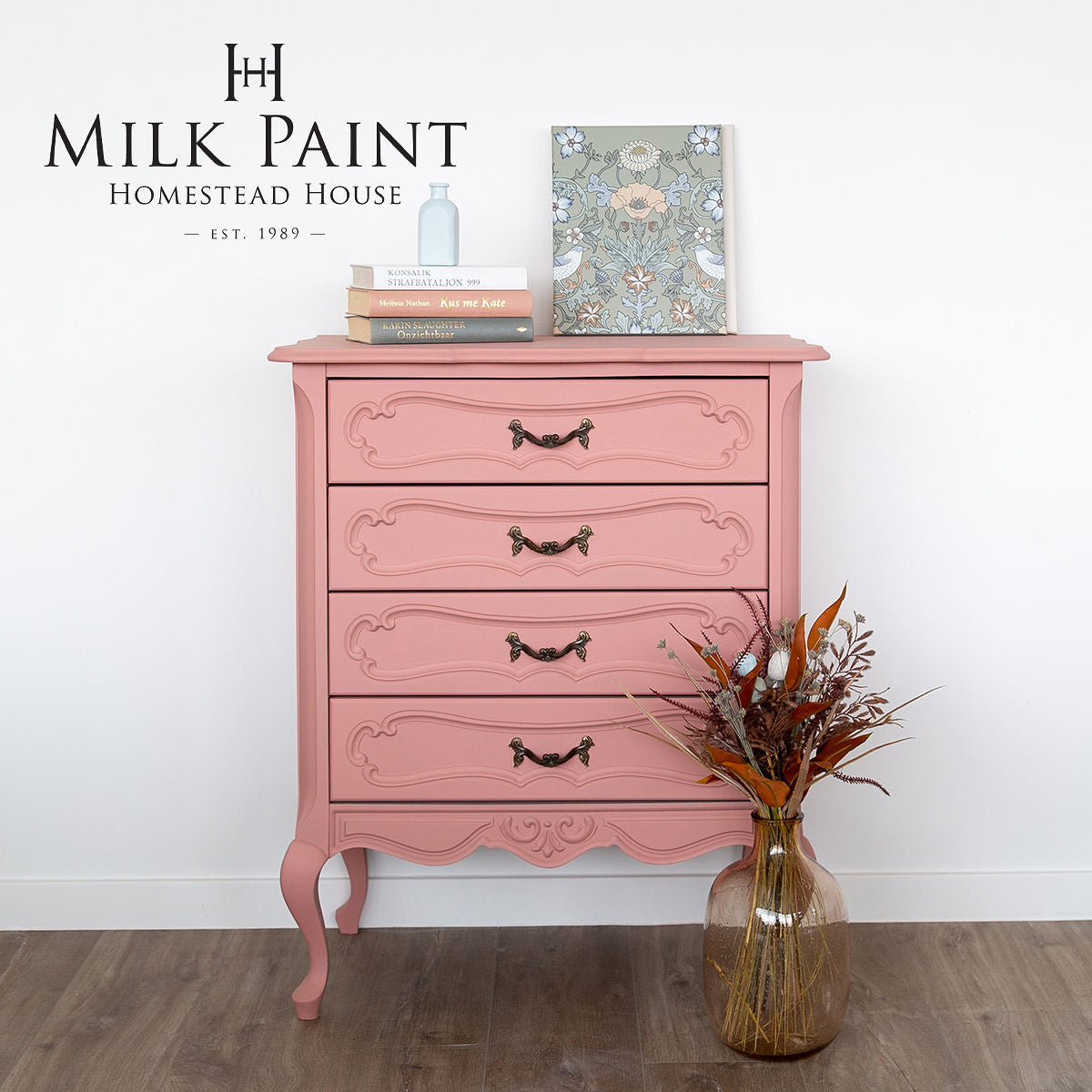 Pink dresser painted with Homestead House Dusty Rose Milk Paint, styled with books, art, and a vase with dried flowers.