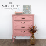 Pink dresser painted with Homestead House Dusty Rose Milk Paint, styled with books, art, and a vase with dried flowers.
