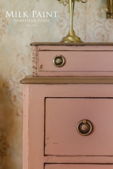 Dresser in Dusty Rose Milk Paint by Homestead House with ornate knobs and a lamp.