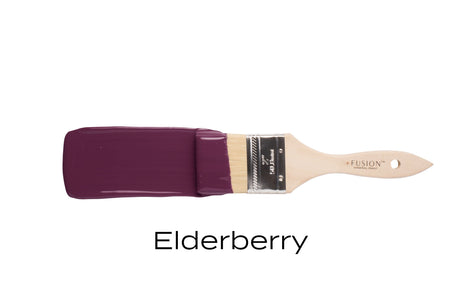 Paintbrush holding Fusion Mineral Paint Elderberry matte acrylic on plain white background.