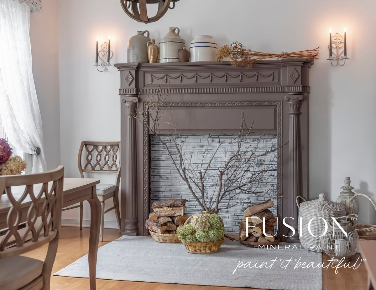 Brown fireplace with stacked wood, chairs, vases, and Elmwood Fusion Mineral Paint logo.