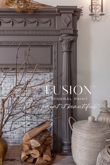 Dark gray ornate fireplace with stacked firewood, wicker basket, and Elmwood Fusion Mineral Paint finish.