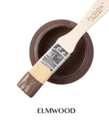 Open Elmwood Fusion Mineral Paint can with brush resting on rim, bristles dipped in paint.