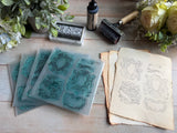 IOD Emblems Mini-Stamp clear stamps by I.O.D., with ink pad, roller, and flowers on vintage bookplate paper.