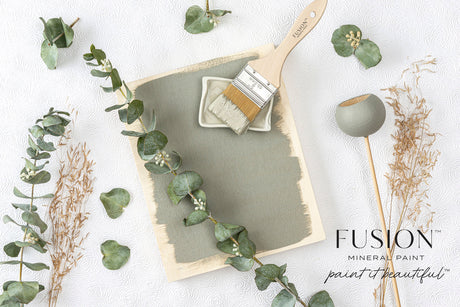 Board partially painted with Eucalyptus Fusion Mineral Paint by Fusion, brush and dried plants beside it.