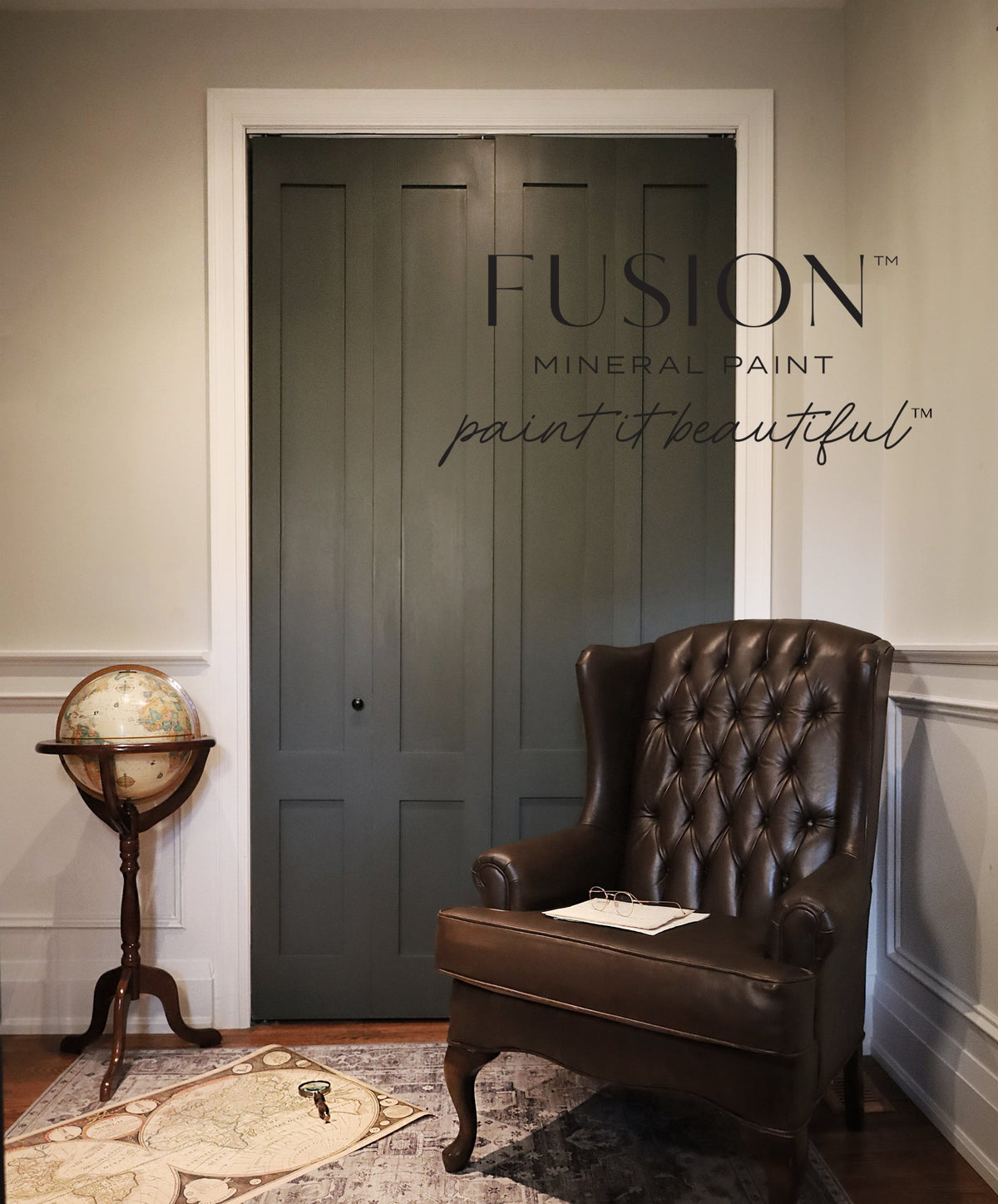 Brown leather armchair and globe beside doors painted in Everett by Fusion Mineral Paint; branding on wall.