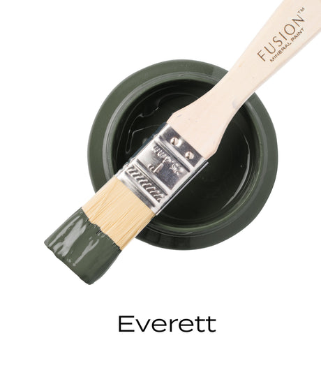 Paintbrush with olive green paint rests on open Everett Fusion Mineral Paint jar by Fusion Mineral Paint.