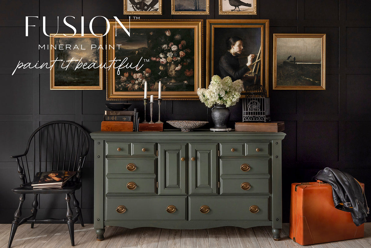 Everett Fusion Mineral Paint shown with gold accents, black chair, orange suitcase, and black wall.