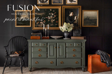 Everett Fusion Mineral Paint shown with gold accents, black chair, orange suitcase, and black wall.
