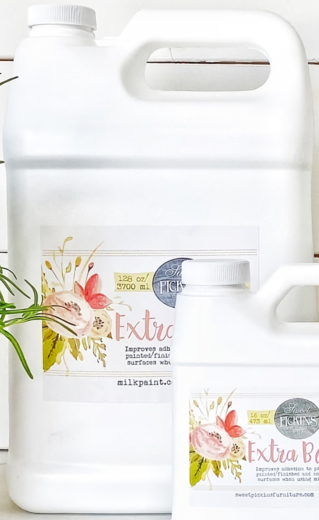Two white bottles of Sweet Pickins Extra Bond Old Fashioned Milk Paint with floral labels on a white surface.