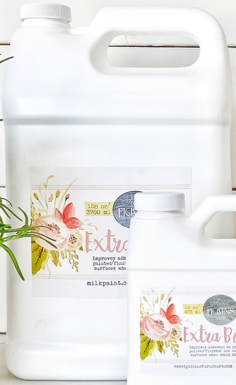 Two white bottles of Sweet Pickins Extra Bond Old Fashioned Milk Paint with floral labels on a white surface.