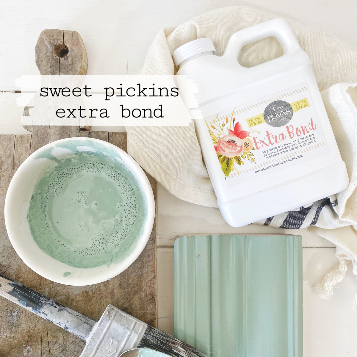 Brush, green paint sample, and Old Fashioned Milk Paint Extra Bond bottle on white background.