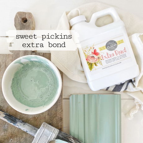 Brush, green paint sample, and Old Fashioned Milk Paint Extra Bond bottle on white background.