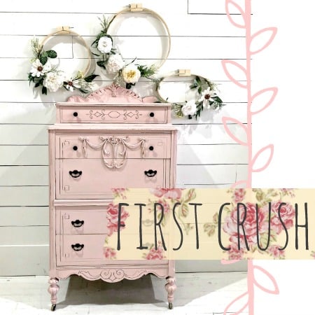 Pink vintage dresser painted with Old Fashioned Milk Paint, decorated with florals, embroidery hoops, and floral banner.