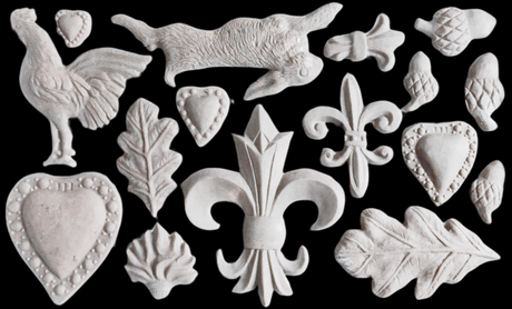 White clay Fleur-de-lis Mould ornaments by I.O.D. displayed on a black background.