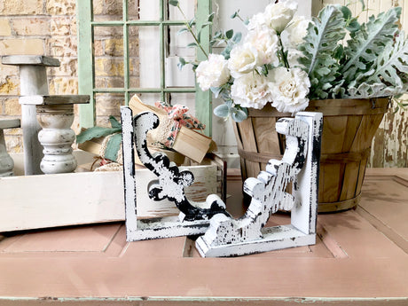 Two Flour Sack brackets by Old Fashioned Milk Paint displayed on a peach table among rustic decor.