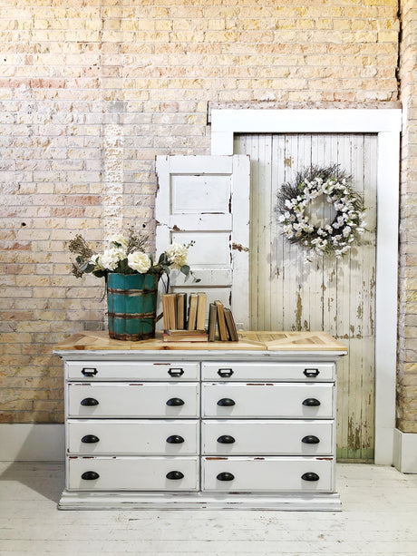 White dresser with books, turquoise vase, and rustic doors painted Flour Sack by Old Fashioned Milk Paint.