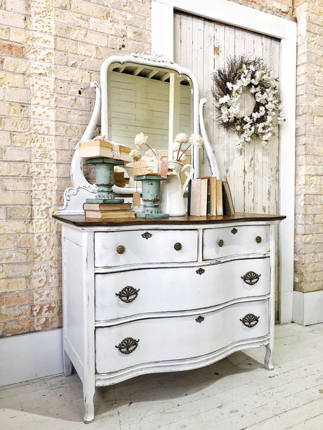 Vintage dresser in Flour Sack by Old Fashioned Milk Paint, styled with books, flowers, and floral wreath on door.