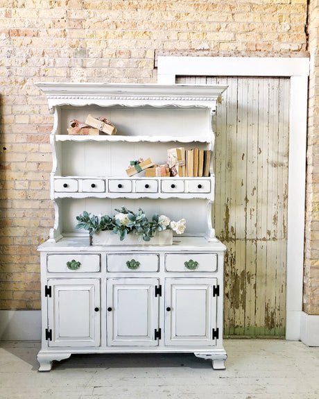 White vintage hutch painted Flour Sack by Old Fashioned Milk Paint, with drawers, shelves, books, and flowers.