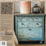 Distressed blue cabinet with large brown vase, small gray bottle, and I.O.D. Folk Story Stamp by Iron Orchid Designs.