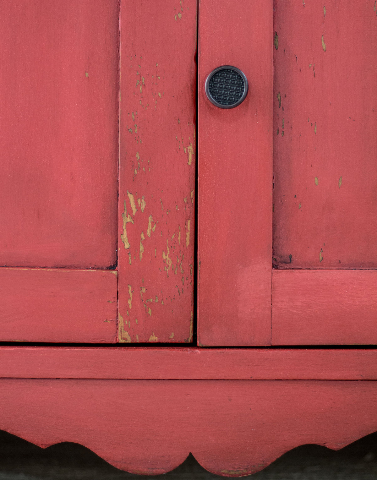 Cabinet in Fort York Red Milk Paint by Homestead House with chipped paint and a black round handle.