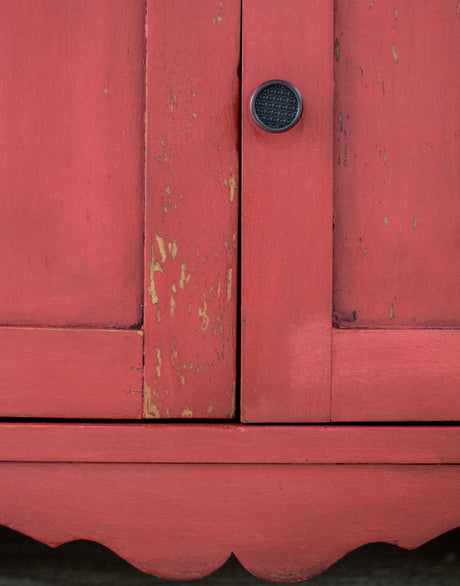 Cabinet in Fort York Red Milk Paint by Homestead House with chipped paint and a black round handle.