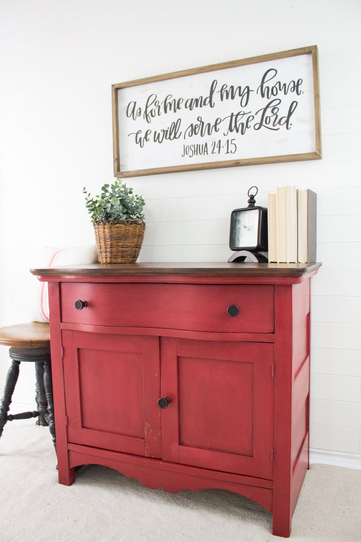 Homestead House Fort York Red cabinet with books, décor, and wall art displaying Joshua 24:15.